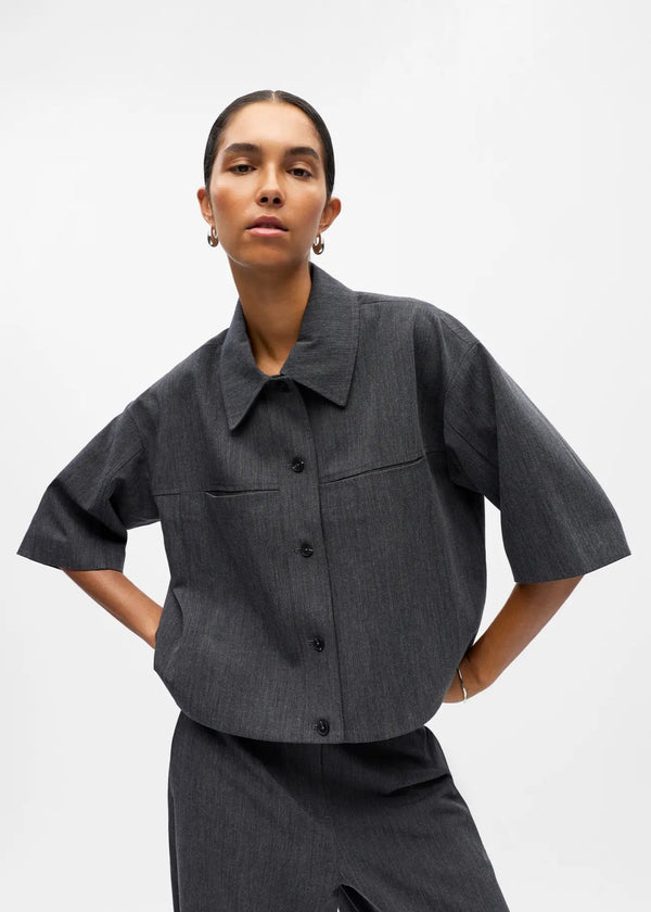 Person wearing a dark gray shirt with short sleeves on a white background