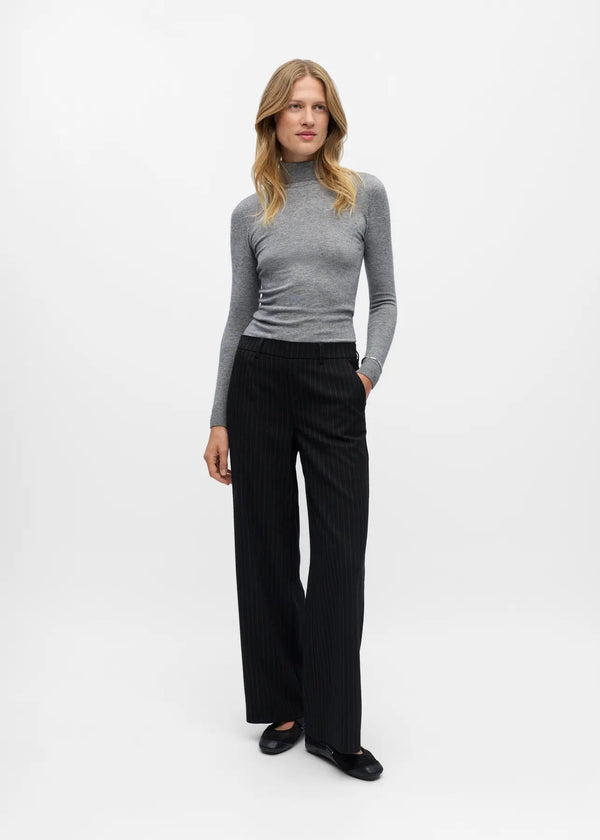 Woman wearing a gray turtleneck and black pants on a white background