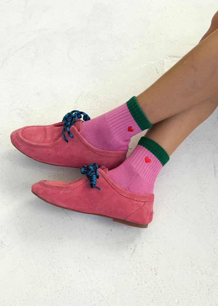 Pink shoes and socks with heart details on a light background