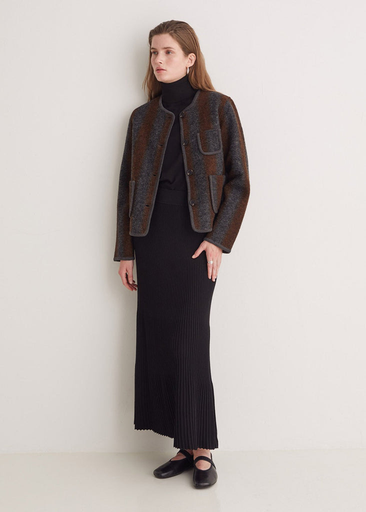 Woman wearing a dark brown jacket over a black outfit on a white background