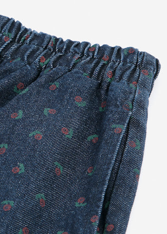 Close-up of a dark blue denim-like fabric with an elastic waistband and a small repeating red and green floral print, shown on a white background.