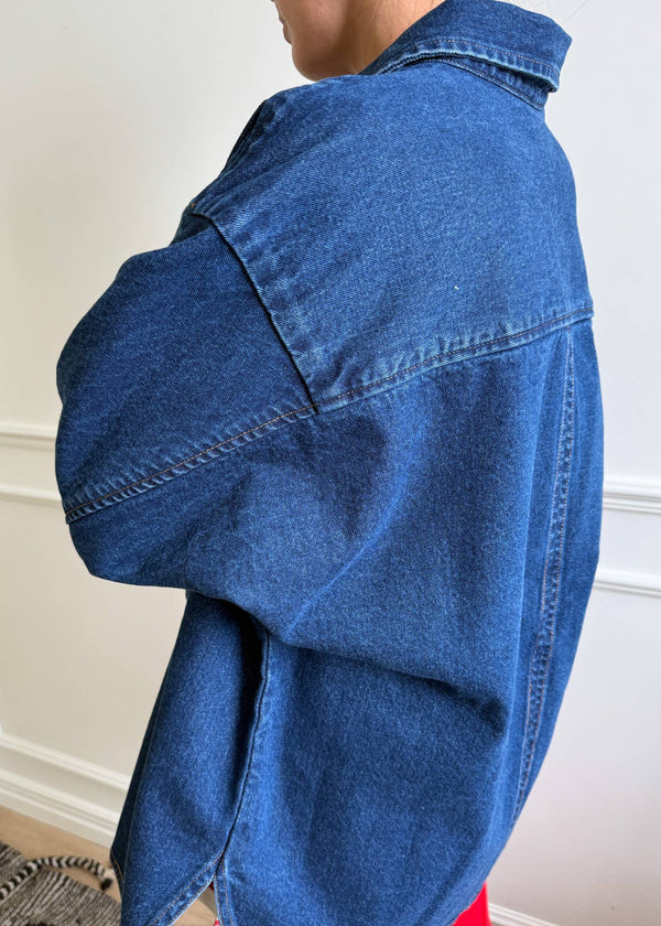 Blue denim jacket worn by a person against a neutral background