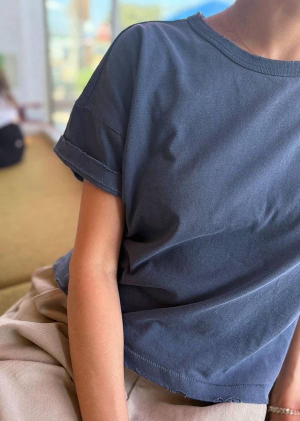 Person wearing a blue t-shirt sitting on a couch with a blurred background