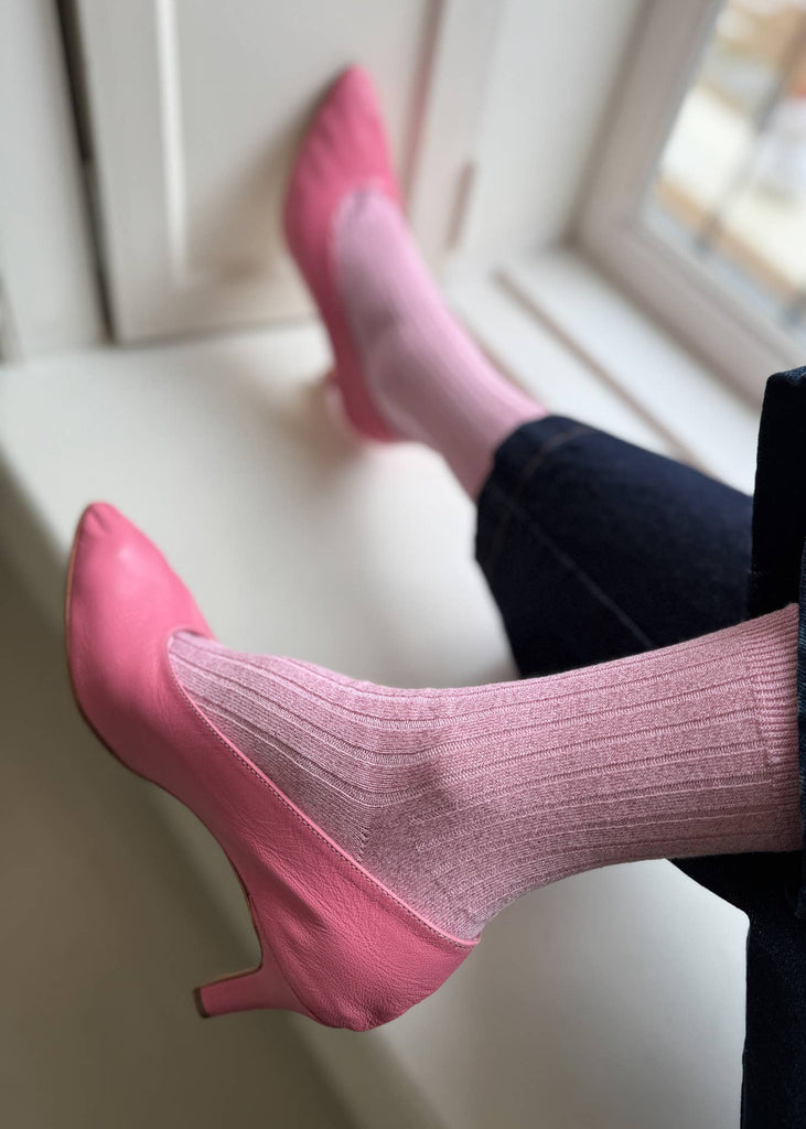 Pink high-heeled shoes and socks on a white surface