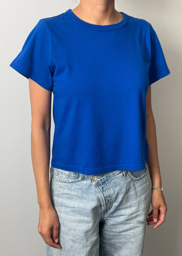 Person wearing a blue t-shirt and light blue jeans against a plain background