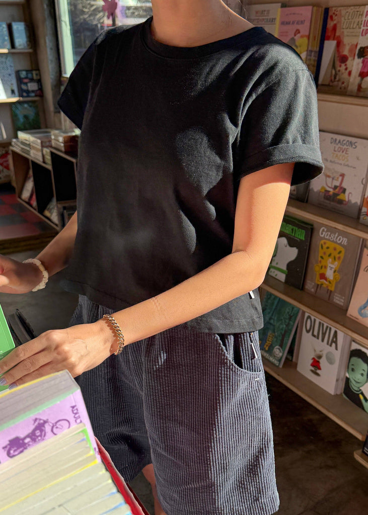 Person wearing a dark t-shirt and shorts in a bookstore setting