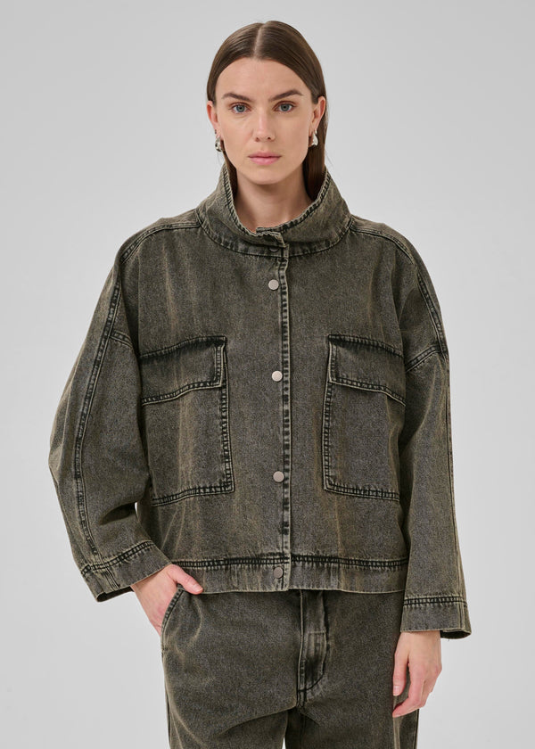 Person wearing a denim jacket on a gray background
