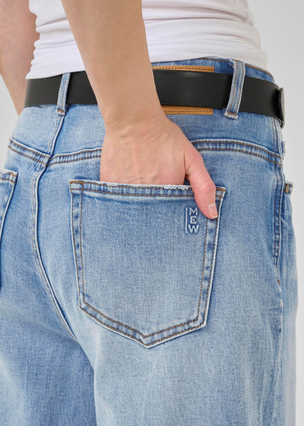 Close-up of blue jeans with a pocket and black belt.