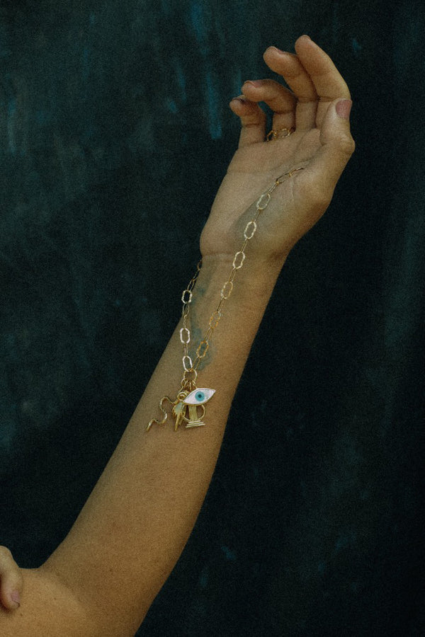 Gold bracelet with a charm on a wrist against a dark background