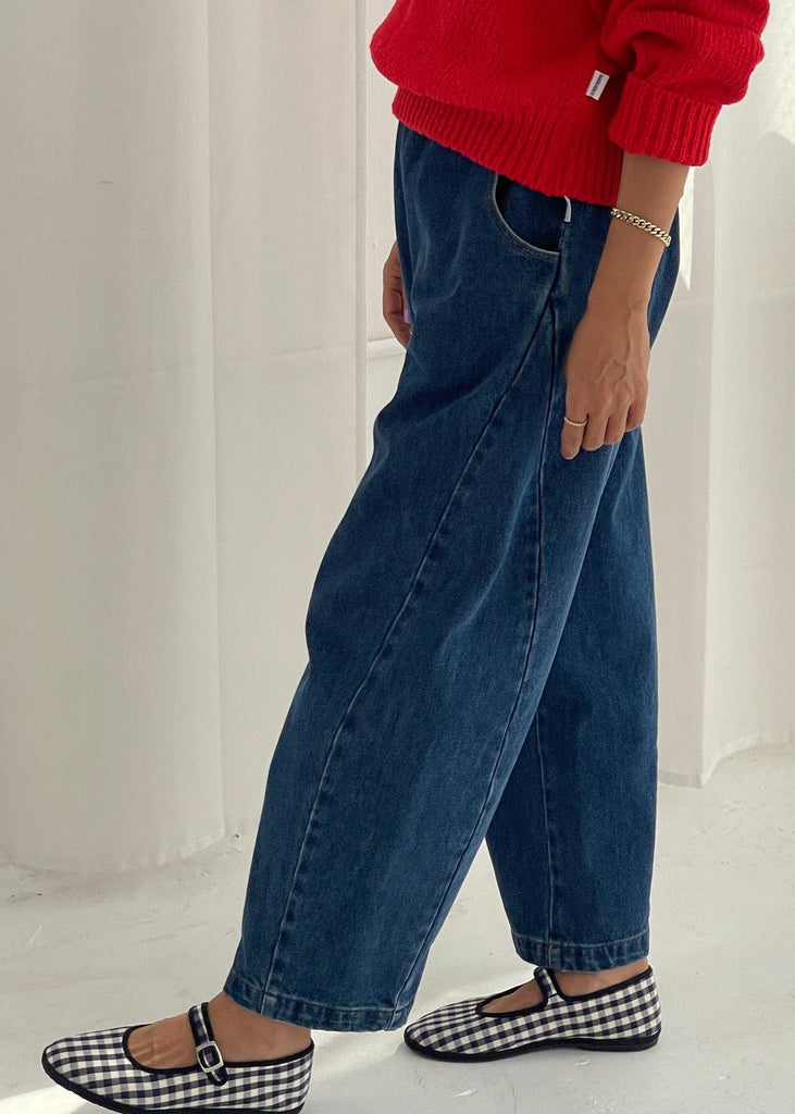 Person wearing a red sweater, blue jeans, and checkered shoes on a white background