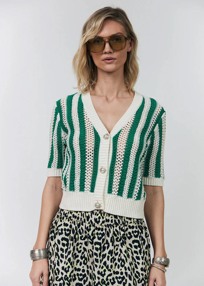 Woman wearing a green and white striped cardigan with a leopard print skirt on a plain background