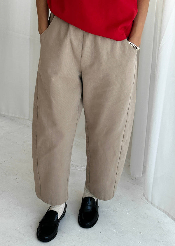 Person wearing beige pants and a red top in a minimalistic setting