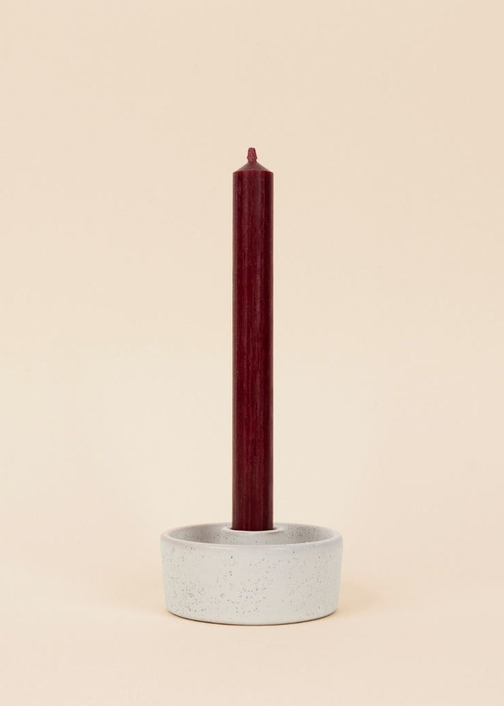 Ceramic candle holder with a red candle on a beige background