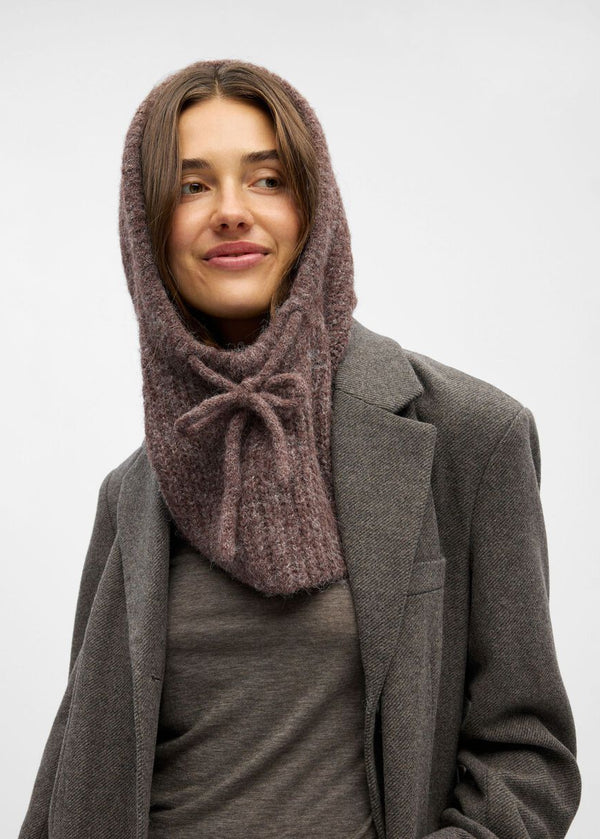 Woman wearing a brown knitted hood over a gray coat on a white background