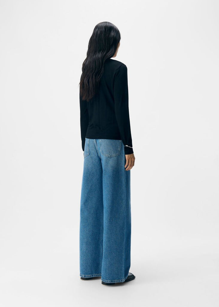 Person wearing a black top and blue jeans on a white background