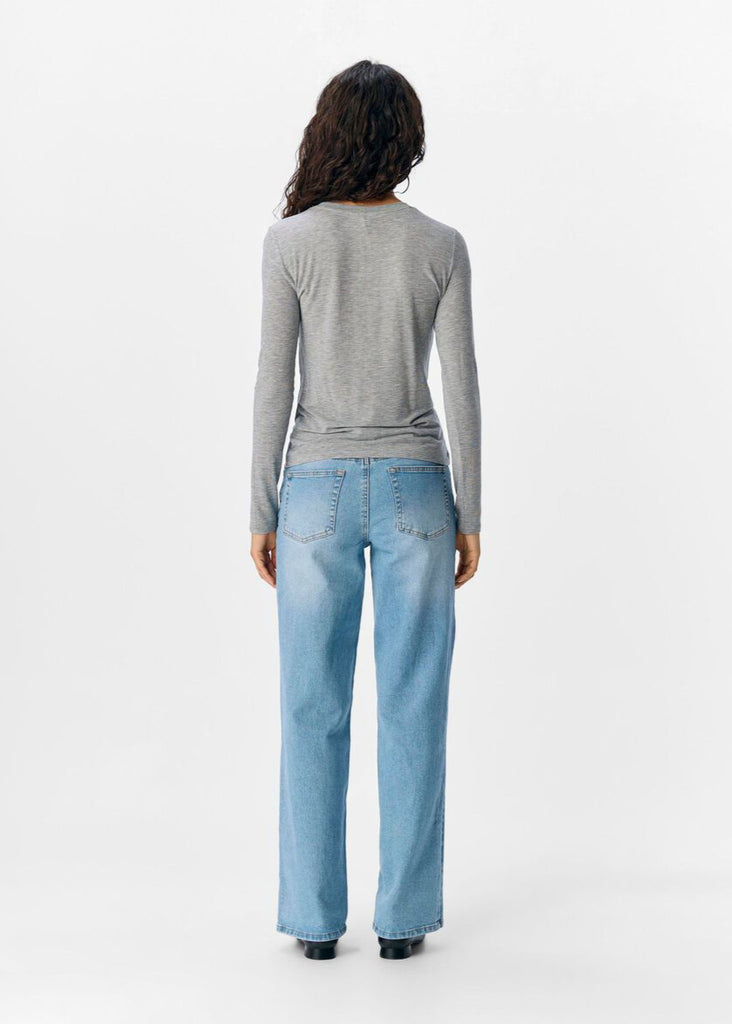 Person wearing a gray long-sleeve top and light blue jeans on a white background