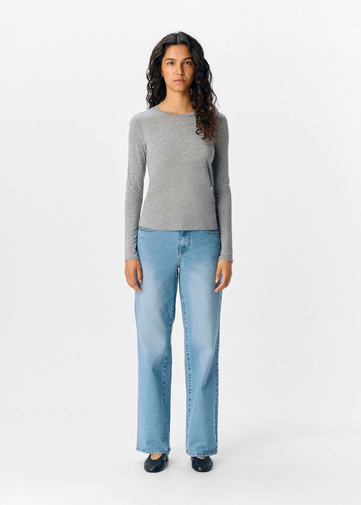 Woman wearing a gray sweater and light blue jeans on a white background