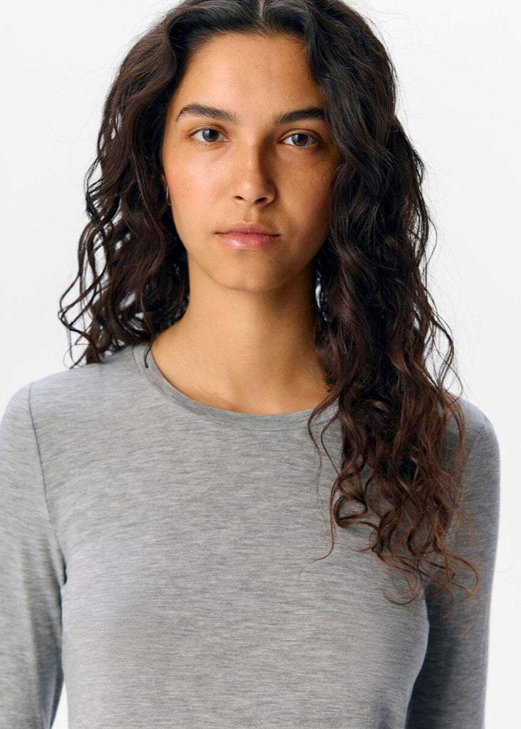 Woman wearing a gray long-sleeve shirt against a white background