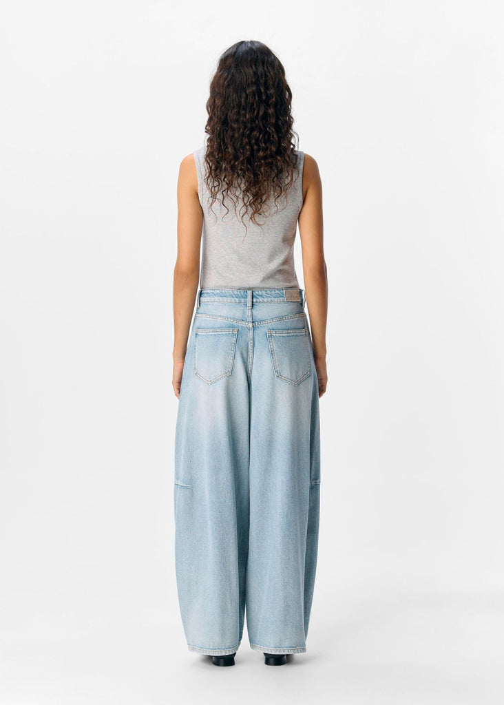 Woman wearing light blue jeans and a gray top on a white background