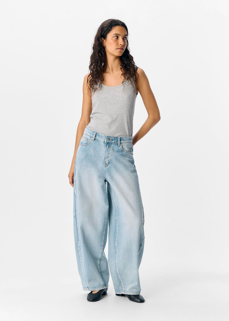 Woman wearing a gray tank top and light blue jeans on a white background