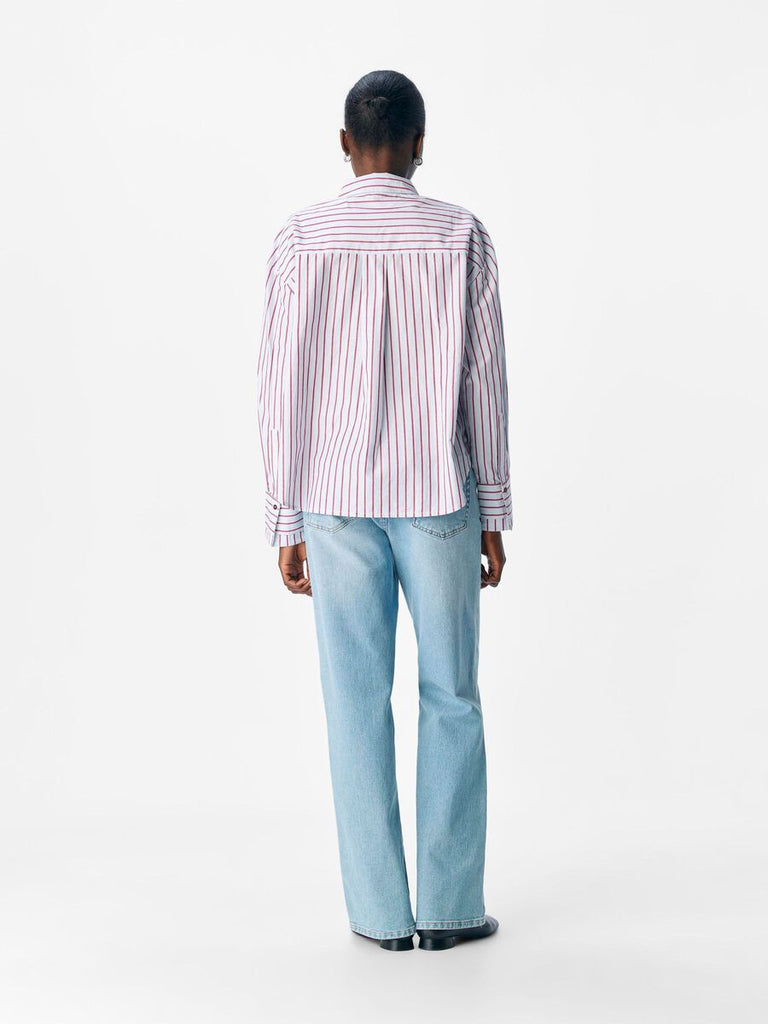 Person wearing a striped shirt and light blue jeans on a white background