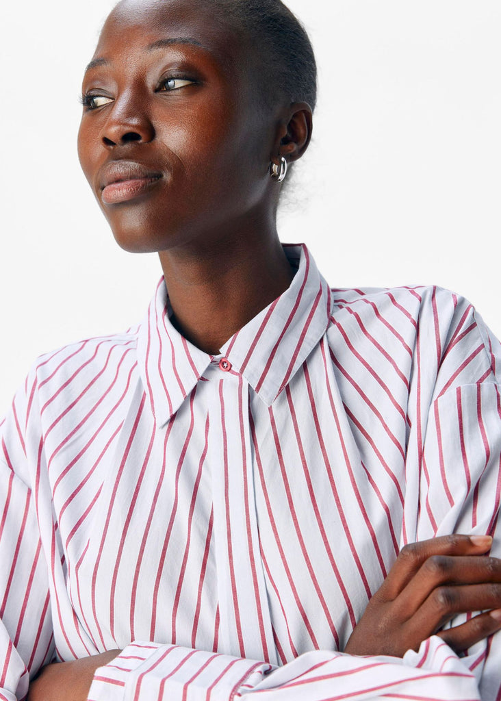 Woman wearing a white shirt with red stripes against a plain background