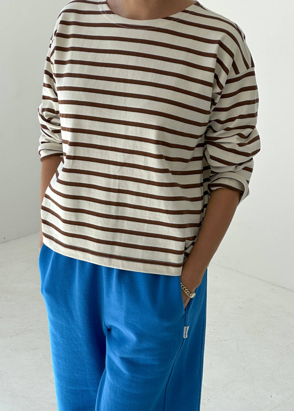 Person wearing a striped shirt and blue pants on a white background