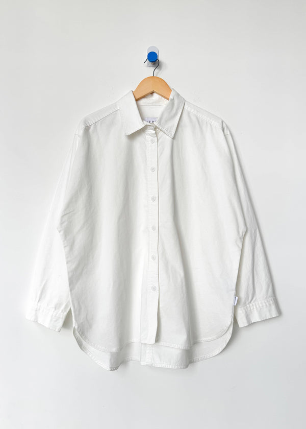 White shirt on a wooden hanger against a white background
