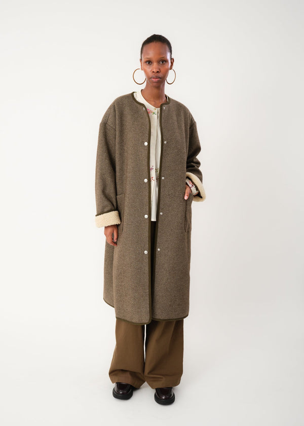 Person wearing a long brown coat on a white background