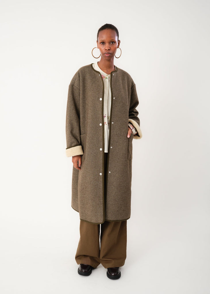 Person wearing a long brown coat on a white background