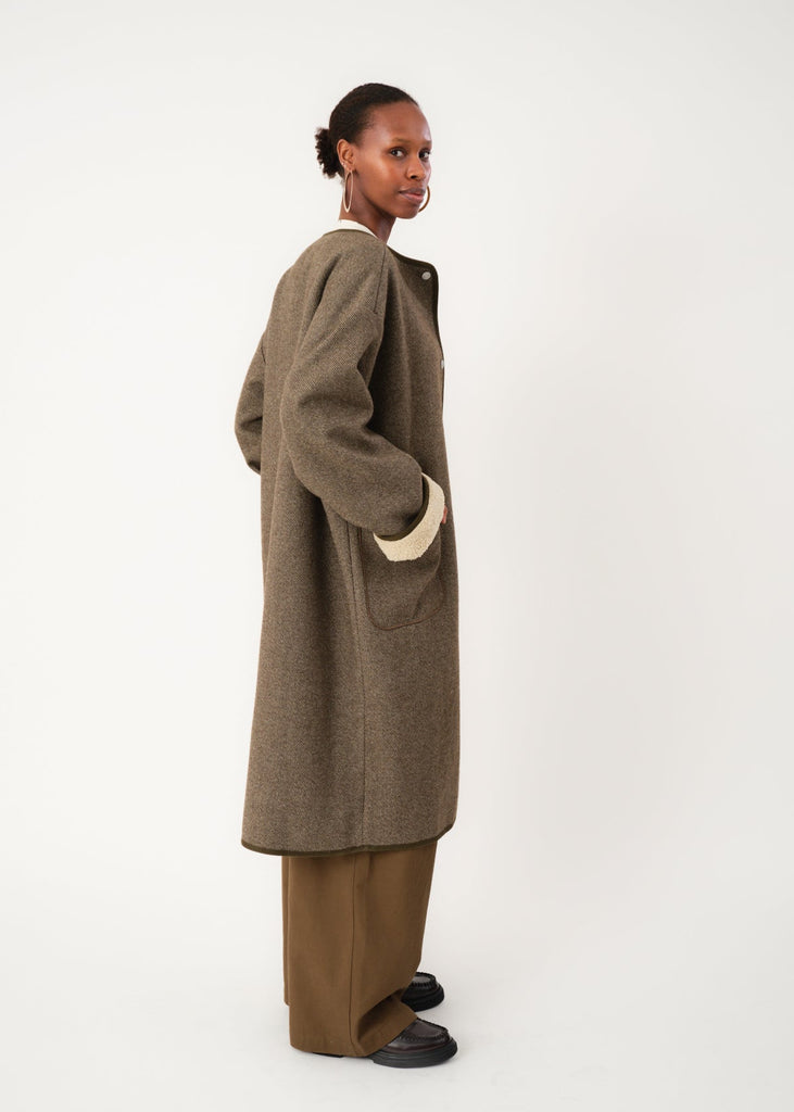 Person wearing a brown coat and pants on a white background