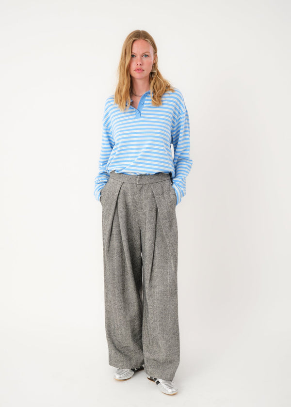 Person wearing a blue striped shirt and gray wide-leg pants on a white background