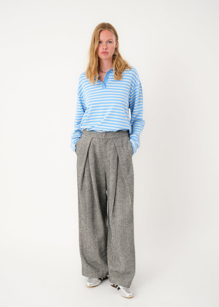 Person wearing a blue striped shirt and gray wide-leg pants on a white background