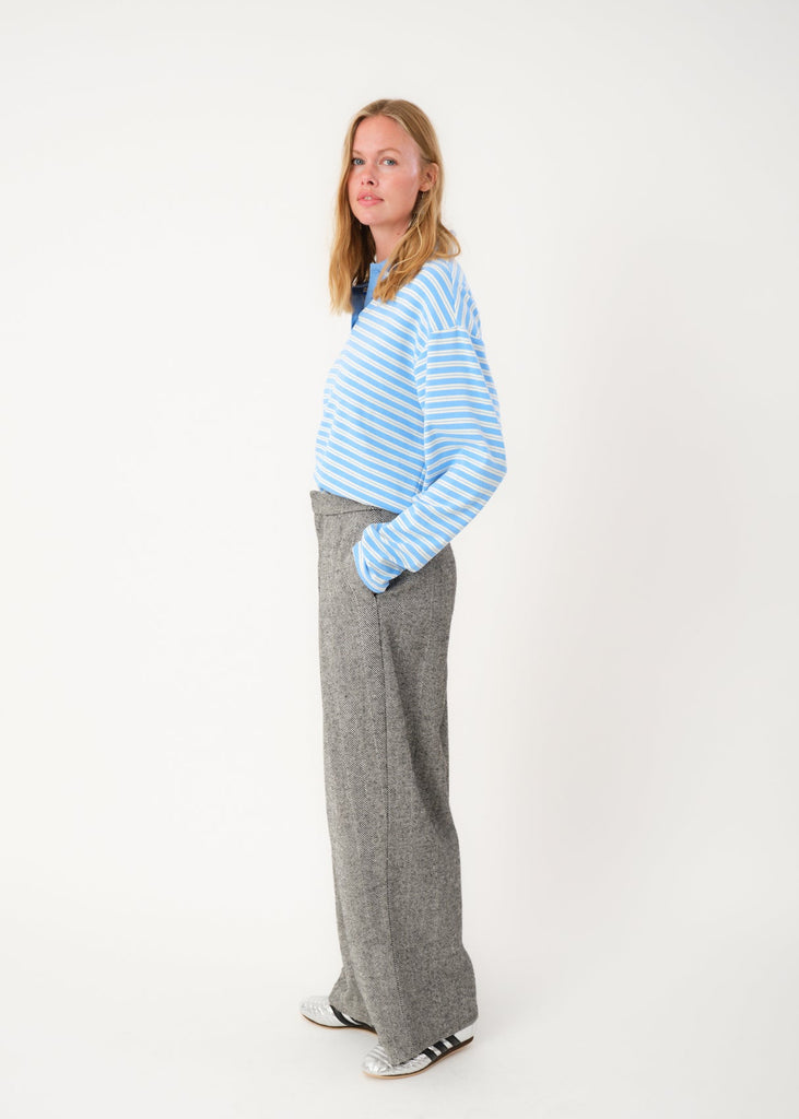 Person wearing a light blue striped sweater and gray pants on a white background