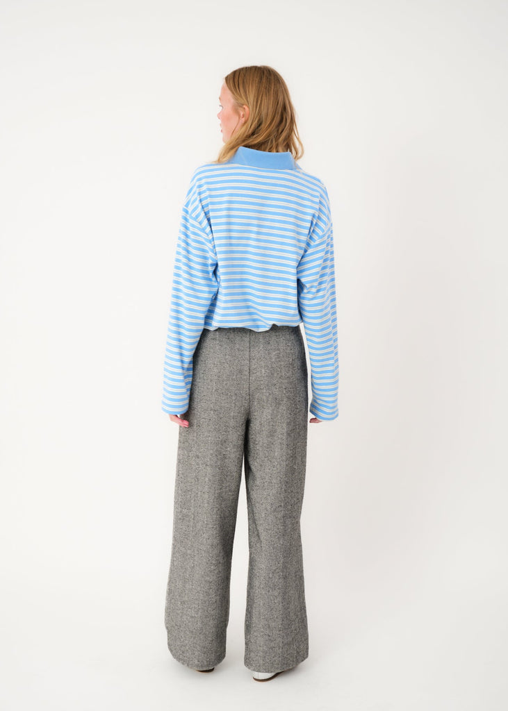 Person wearing a blue and white striped sweater and gray pants on a white background