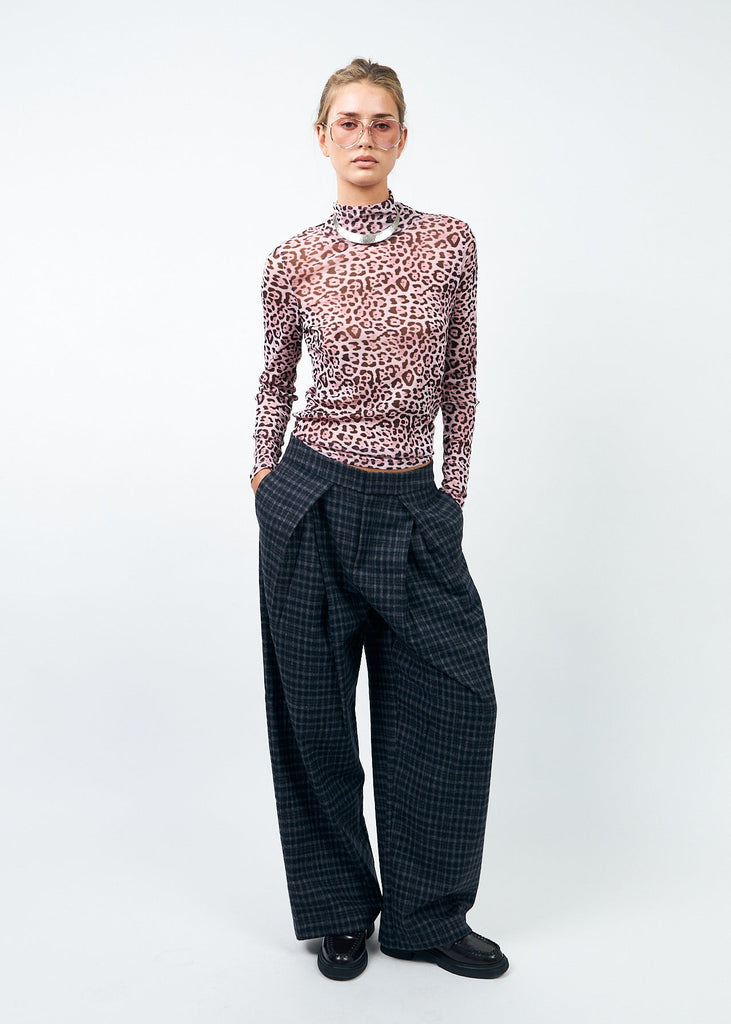 Person wearing a patterned top and checkered pants on a white background