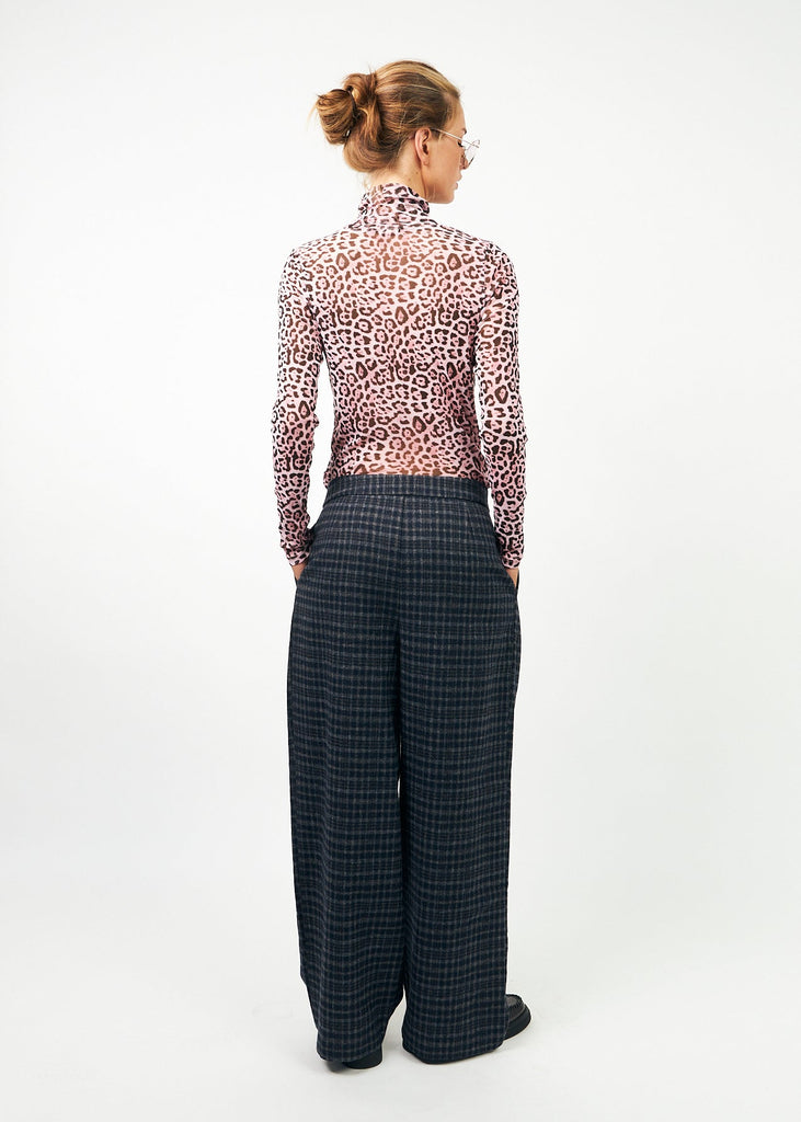 Woman wearing a leopard print blouse and checkered pants on a white background