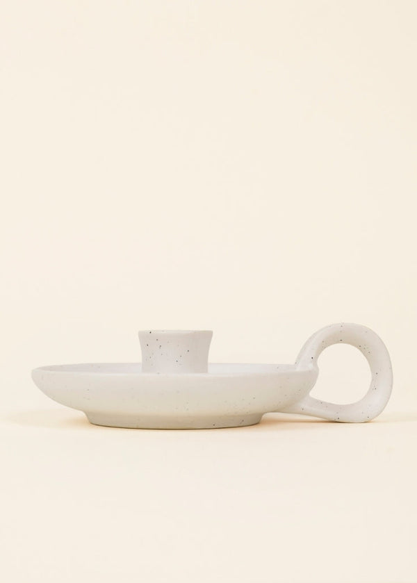 White ceramic dish with handle on a beige background