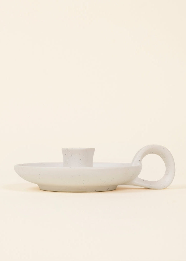 White ceramic dish with handle on a beige background