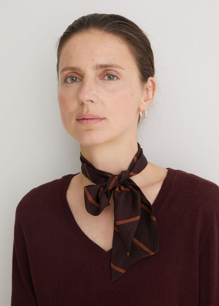 Woman wearing a brown scarf around her neck against a white background