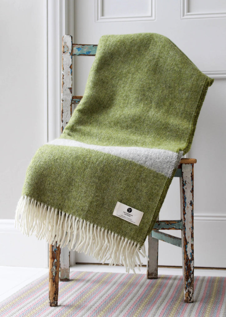 Green blanket draped over a wooden chair with a white background