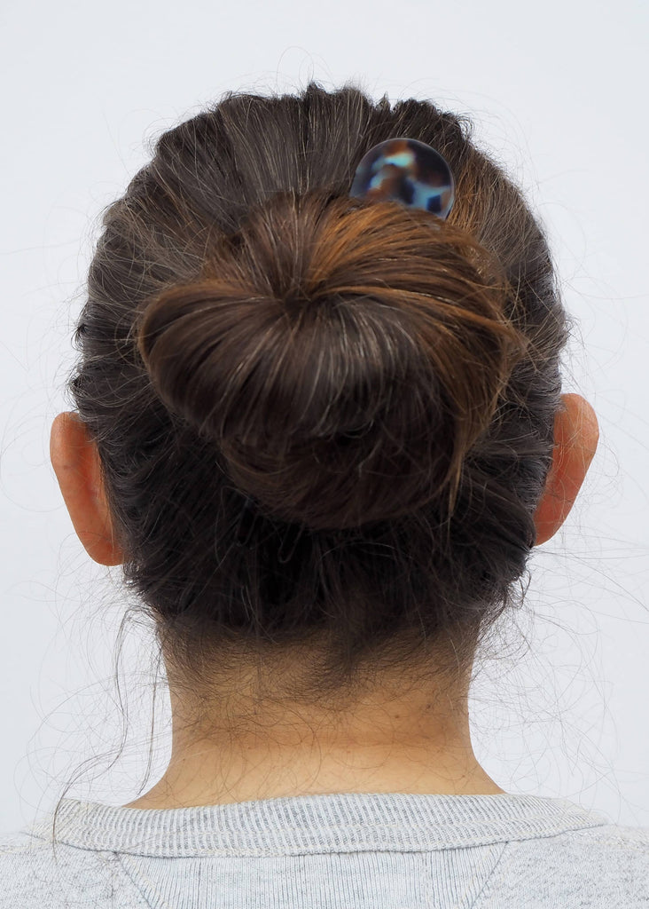 Back view of a person with a bun and hair clip on a white background