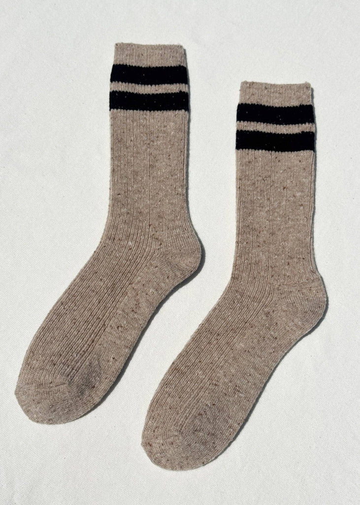 Pair of beige socks with black stripes on a light gray background