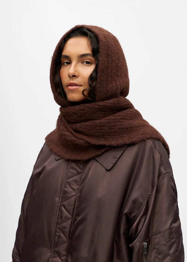 Person wearing a brown hooded coat and scarf on a white background