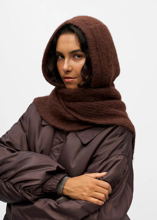 Person wearing a brown hooded garment against a white background
