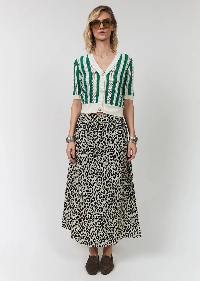 Woman wearing a green and white striped cardigan with a leopard print skirt on a white background