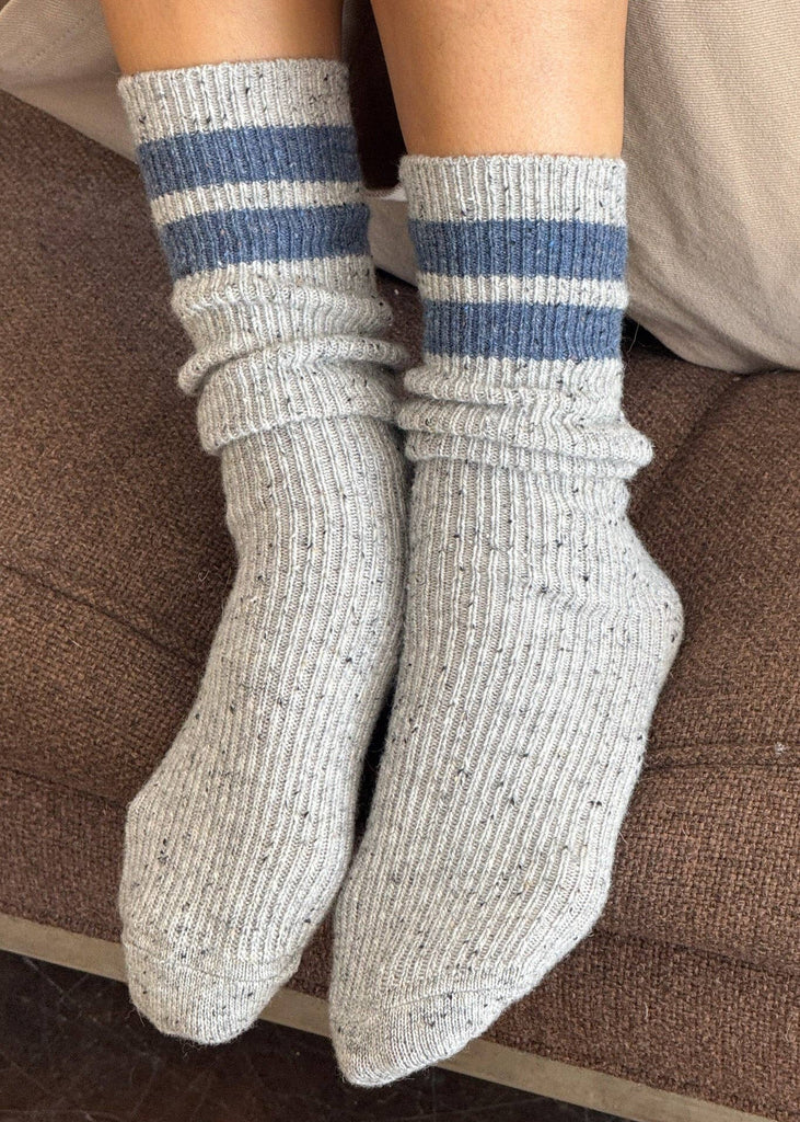 Gray socks with blue stripes worn on a brown textured surface