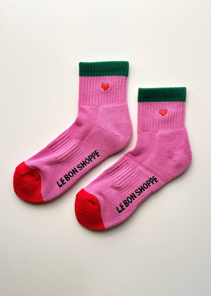 Pink socks with green crowns and red toes on a light gray background