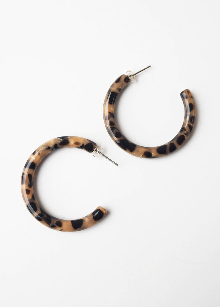 Pair of tortoiseshell hoop earrings on a white background