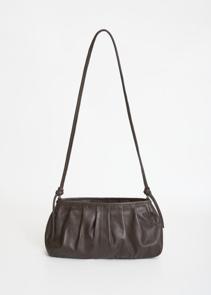Dark brown leather handbag with a shoulder strap on a light gray background